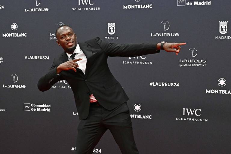 Foto de Javier Soriano mostra Usain Bolt vestindo um terno preto com gravata da mesma cor e uma camisa branca. Bolt é um homen negro de pele retinta, careca e com um cavanhaque. Ele está fazendo a "pose de raio" que marcou sua carreira de atleta. 