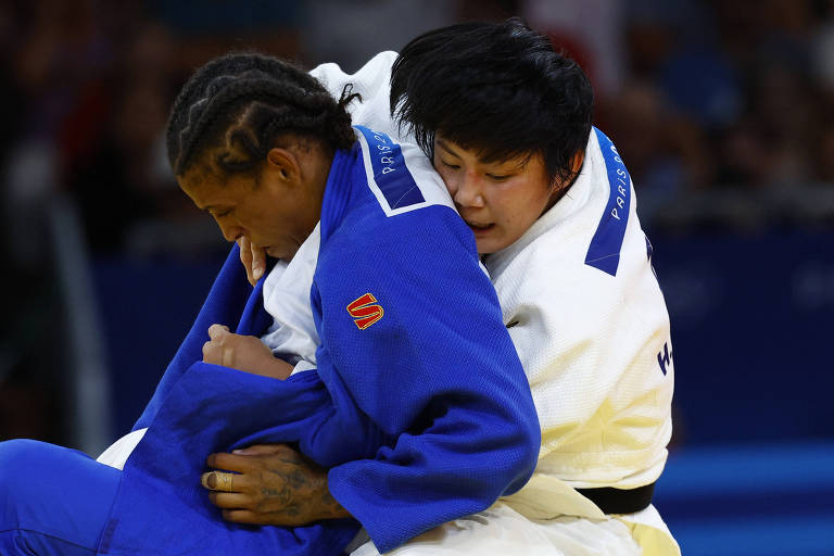 Rafaela Silva, usando quimono azul, é agarrada pela japonesa Haruka Funakubo, que usa branco, na luta pela medalha de bronze nas Olimpíadas de Paris
