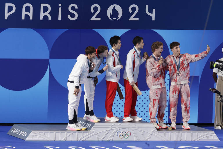 Medalhistas do salto ornamental sincronizado na plataforma de 10 m posam para selfie sobre o pódio. São eles os britânicos Tom Daley e Noah Williams, os chineses Yang Hao e Lian Junjie e os canadenses Rylan Wiens e Nathan Zsombor-Murray