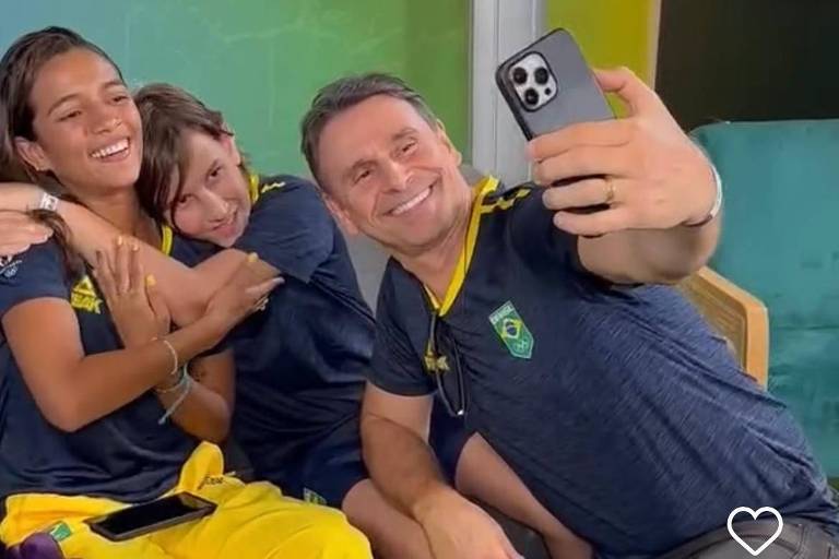 Crianças se abraçam e homem faz selfie com celular