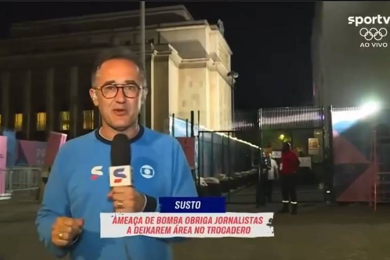 Homem de camisa azul, óculos e microfone na mão