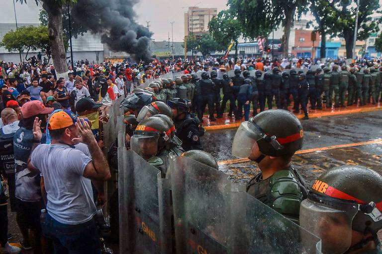 Barreira policial detém manifestantes durante protesto em Puerto La Cruz na segunda-feira (29); órgão que anunciou vitória de Maduro tem histórico de manobras contra oposição