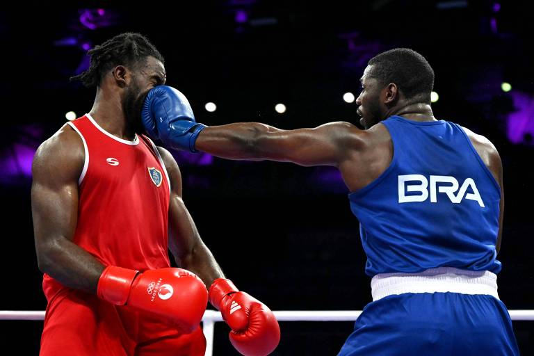 Usando uniforme azul com a inscrição BRA nas costas, o boxeador brasileiro Wanderley "Holyfield" Pereira acerta golpe no haitiano Cedrick Belony-Duliepre, que está de vermelho, em luta nas Olimpíadas de Paris 