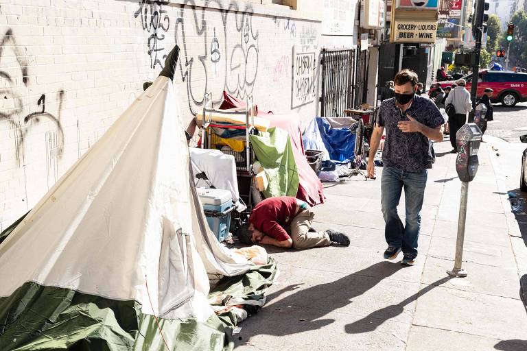 Pedestre passa por barracas montadas em uma calçada