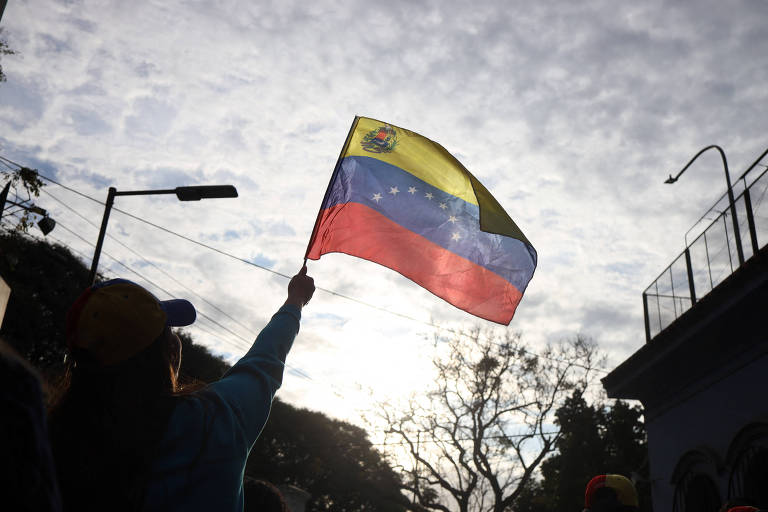 Venezuelano segura bandeira de seu país na embaixada da Venezuela em Buenos Aires