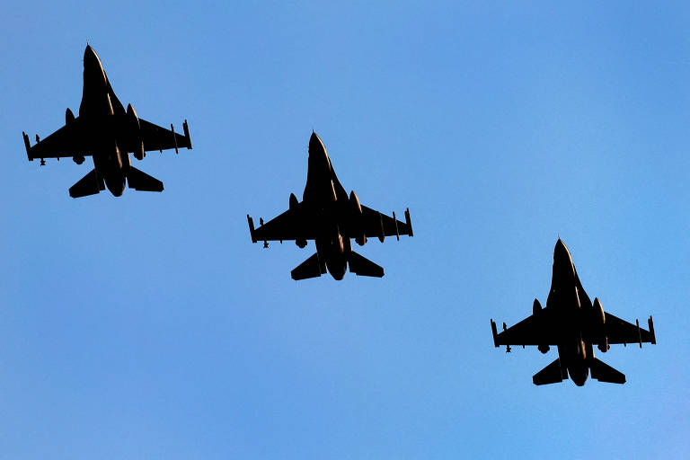 Em um céu azul, a silhueta de três aviões de combate escuros