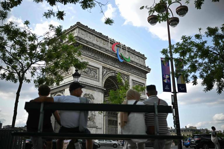 Turistas sentados em frente ao Arco do Triunfo, em Paris
