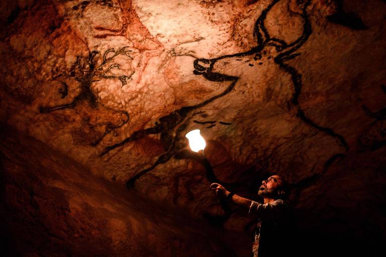 Visitante diante de réplica das pinturas rupestres de Lascaux, na França 