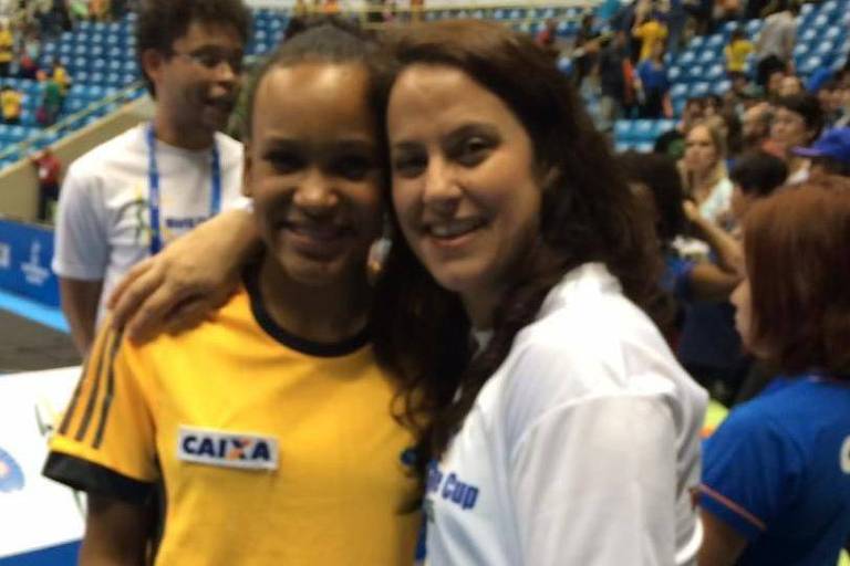 Rebeca criança e Monica se abraçam num ginásio