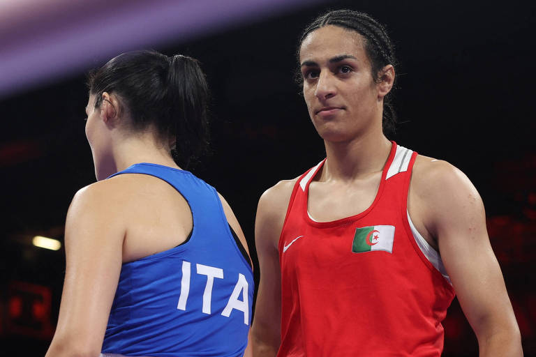 A imagem mostra duas boxeadoras em um ringue. A atleta à esquerda está vestindo um uniforme azul com a inscrição 'ITA', representando a Itália. A atleta à direita está vestindo um uniforme vermelho, com um olhar focado. Ambas estão em uma posição de espera, com o fundo desfocado, sugerindo um ambiente de competição.