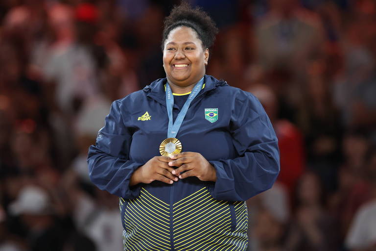 A judoca Beatriz Souza (acima de 78 kg), no pódio, sorri e segura a medalha de ouro, a primeira do Brasil nas Olimpíadas de Paris