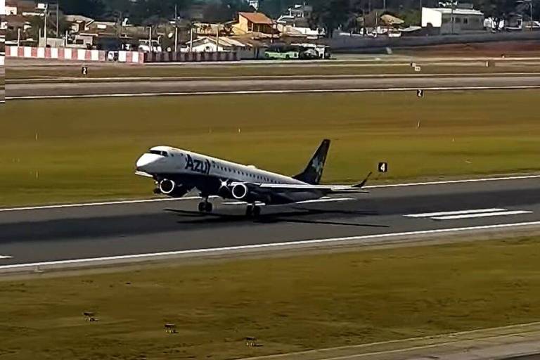 Um avião da companhia aérea Azul na pista de um aeroporto. O avião está com as rodas traseiras tocando o solo, enquanto a dianteira ainda está no ar