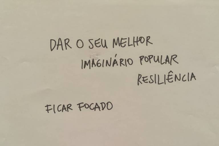 Uma folha de papel com texto escrito à mão. As frases incluem: 'DAR O SEU MELHOR', 'IMAGINÁRIO POPULAR', 'RESILIÊNCIA' e 'FICAR FOCADO'. O fundo é de cor clara.