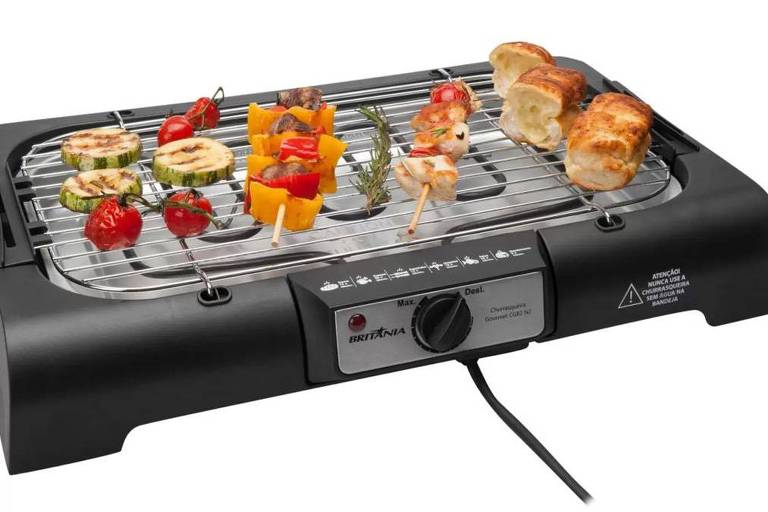 Imagem de fundo branco mostra uma churrasqueira portátil preta com espetinhos de cubos de frango e legumes na grelha.