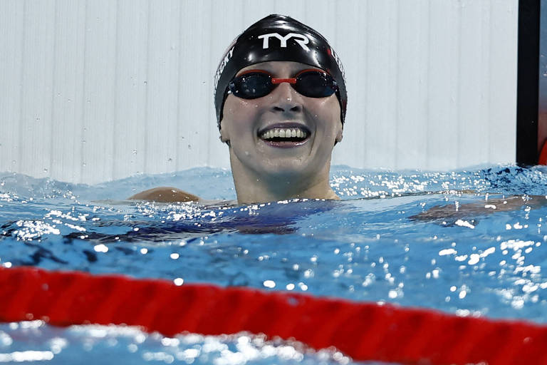 Katie Ledecky, dos EUA, usando touca e óculo de natação, sorri dentro da piscina depois de ganhar os 800 m livre nas Olimpíadas de Paris
