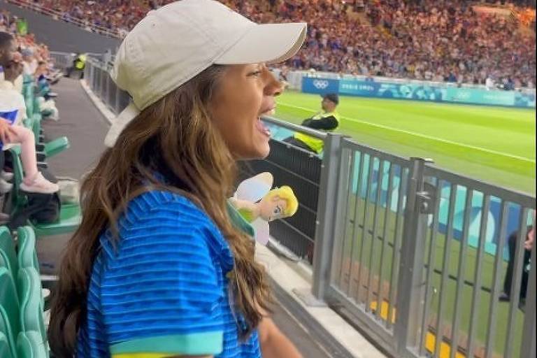 Em foto colorida, mulher vibra com vitória do Brasil no futebol