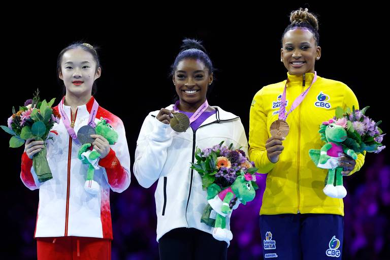 Zhou Yaqin (China, prata), Simone Biles (EUA, ouro) e Rebeca Andrade (Brasil, bronze) sorriem e mostra suas medalhas no pódio da trave no Mundial de ginástica artística de 2023, na Antuérpia (Bélgica)