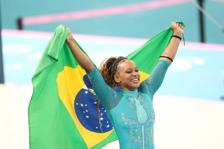 Rebecca Andrade levanta bandeira do Brasil após ganhar medalha de ouro na ginástica artística. 