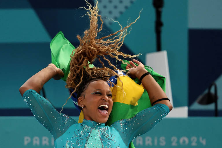 Mulher negra com roupa verde e bandeira verde e amarela sorri