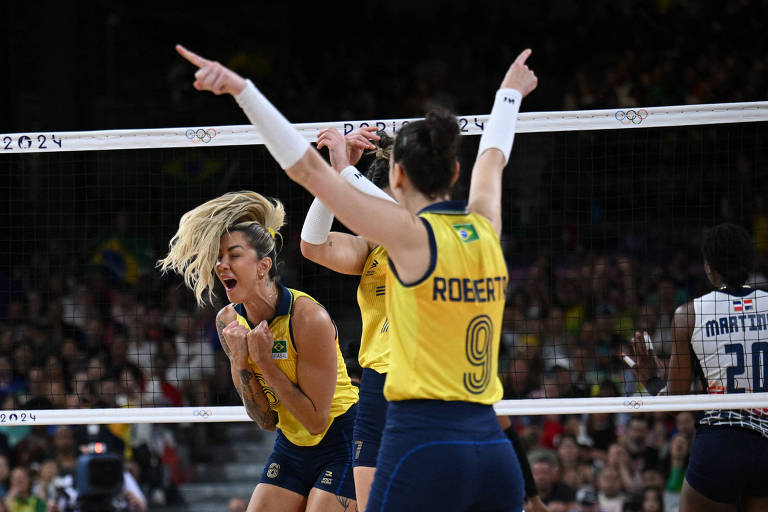 Thaísa, com o rabo de cavalo caindo sobre o rosto, e Roberta, de costas e com os braços erguidos, vibram na vitória da seleção brasileira de vôlei sobre a República Dominicana nas quartas de final das Olimpíadas de Paris