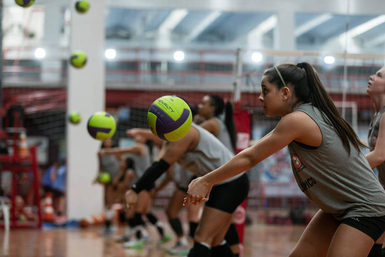 Mulheres treinam manchete no vôlei em uma quadra 