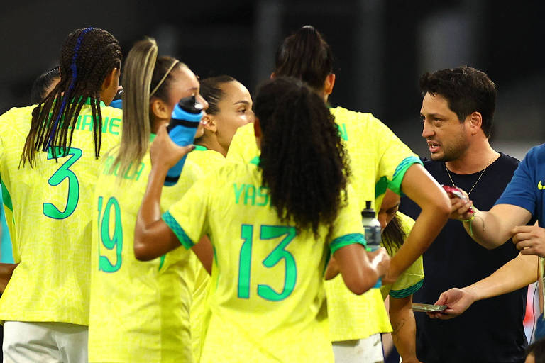 O técnico Arthur Elias, usando camiseta preta, orienta cinco jogadoras da seleção brasileira de futebol, todas usando camisa amarela, na semifinal diante da Espanha nos Jogos Olímpicos da França