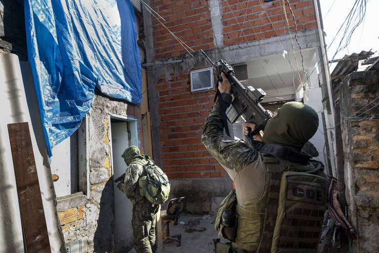 Dois policiais com uniformes camuflados apontam suas armas em um local que parece ser um beco 