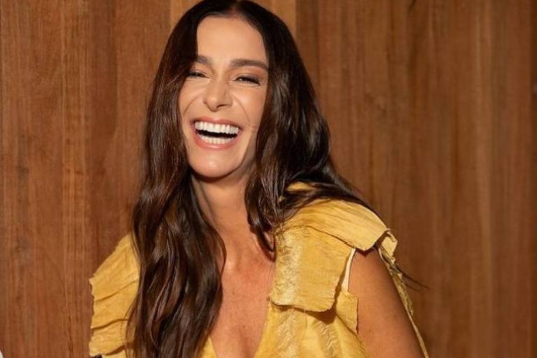 Em foto colorida, mulher vestida de amarelo posa para foto