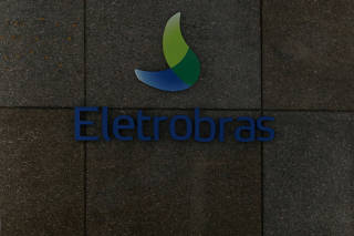 FILE PHOTO: A person stands next to the logo of Brazil's power company Eletrobras in Rio de Janeiro