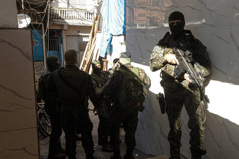 A imagem mostra um grupo de homens armados, aparentemente membros de uma força de segurança, em um ambiente urbano. Um dos homens está em destaque, de pé, com um rifle e usando uma máscara. Os outros estão em movimento, com mochilas e equipamentos, em um espaço que parece ser uma rua ou beco.