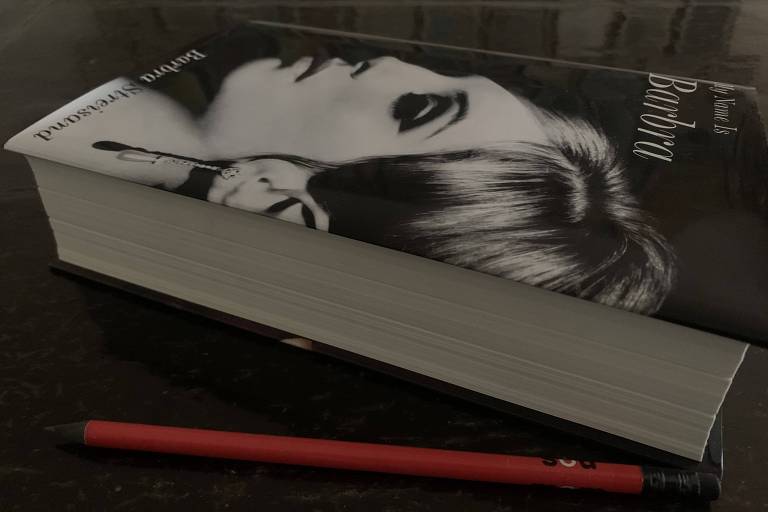 A imagem mostra um livro de capa dura, com o título My Name is Barbra, com uma fotografia em preto e branco de uma mulher, a atriz Barbra Streisand jovem,  na capa. O livro está apoiado em uma superfície escura, e ao lado dele há uma caneta vermelha.
