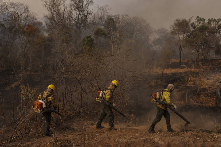 Três homens no combate ao fogo， usando roupas de proteção， em local com fumaça