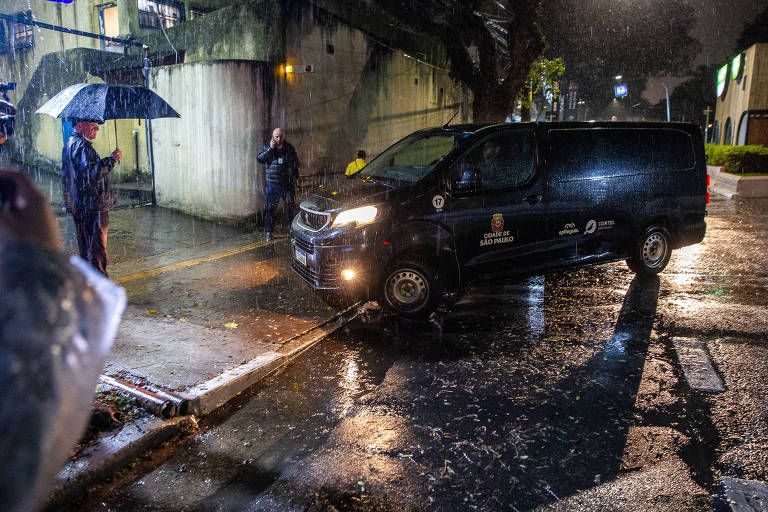 Van preta entra em portão em noite de chuva