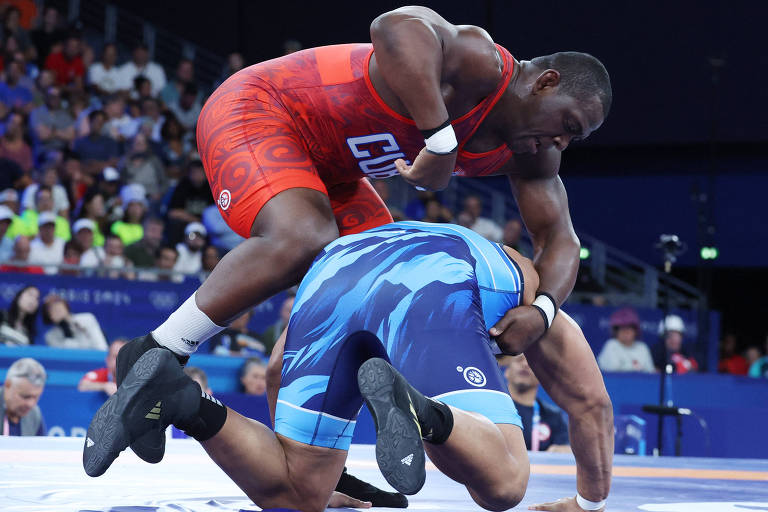 Usando uniforme vermelho na Arena do Campo de Marte, o cubano Mijaín López tenta aplicar golpe no chileno Yasmani Acosta na disputa do ouro da categoria até 130 kg da luta greco-romana nos Jogos Olímpicos de Paris