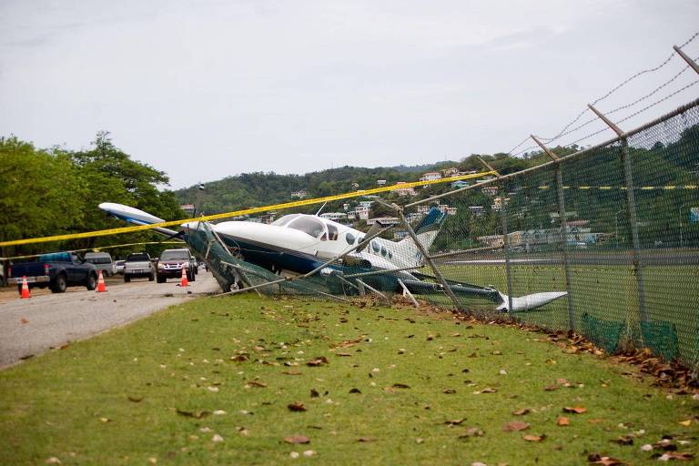 Fotografia de avião caido em cima de uma cerca
