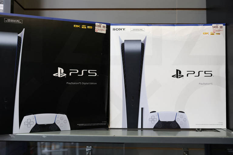 A imagem mostra duas caixas do console PlayStation 5, uma na cor preta e outra na cor branca, ambas exibindo o logotipo do PS5 na parte frontal. As caixas estão posicionadas em uma prateleira, com a caixa preta à esquerda e a caixa branca à direita.