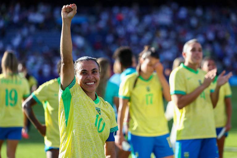 Com o braço direito erguido e o punho cerrado, Marta comemora sorrindo a conquista da medalha de prata pela seleção brasileira nos Jogos Olímpicos de Paris