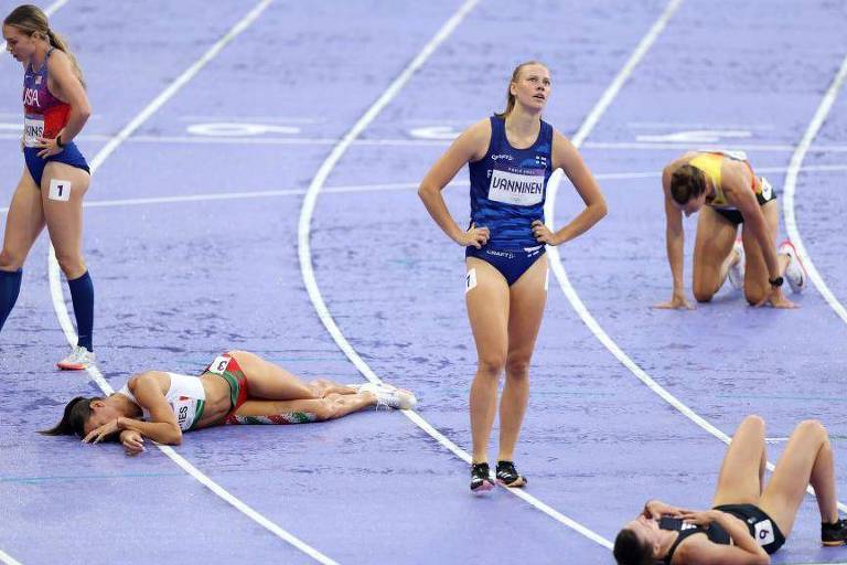 Atletas exaustas deitadas na pista após competir no heptatlo feminino nos Jogos Olímpicos de Paris 2024
