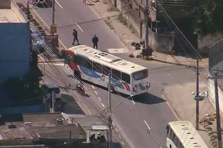 Ônibus branco, vermelho e azul atravessado na diagonal em uma rua