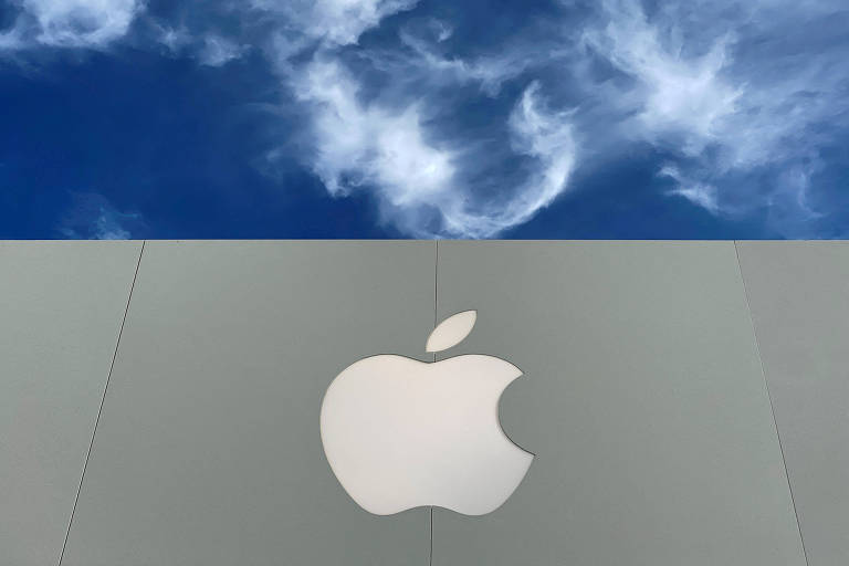 A imagem mostra o logotipo da Apple em um fundo cinza, com um céu azul e nuvens brancas visíveis na parte superior. O logotipo é grande e centralizado na parte inferior da imagem.
