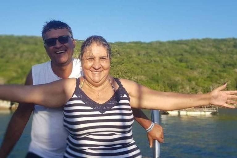 casal sorrindente em frente a lago 