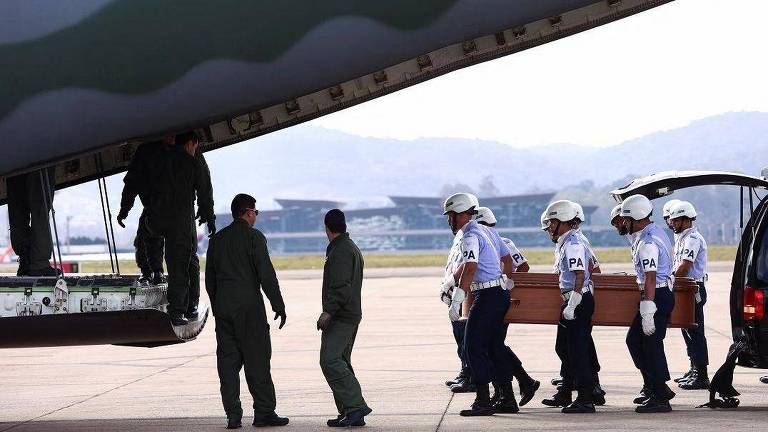 A imagem mostra seis homens da Força Aérea, carregando um caixão em direção a um avião