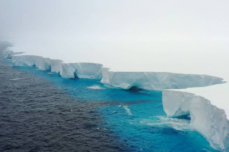 Vista de cima de uma borda do iceberg; a água tem cor azul clara perto da borda