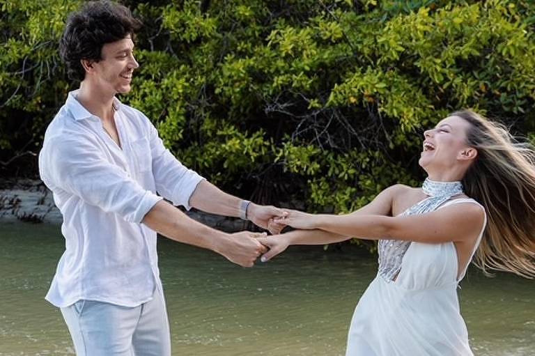 Casal sorridente e de mãos dadas na praia 