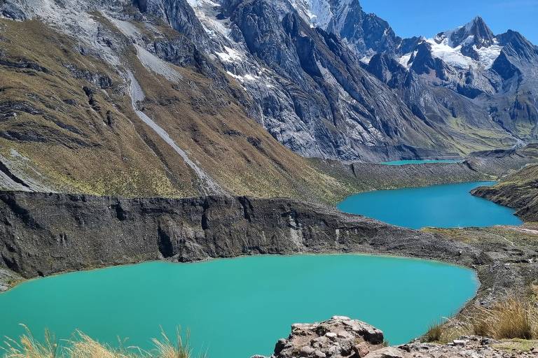 Imagem mostra três lagoas azul turquesa em série. Do lado esquerdo aparece uma sequência de montanhas nevadas