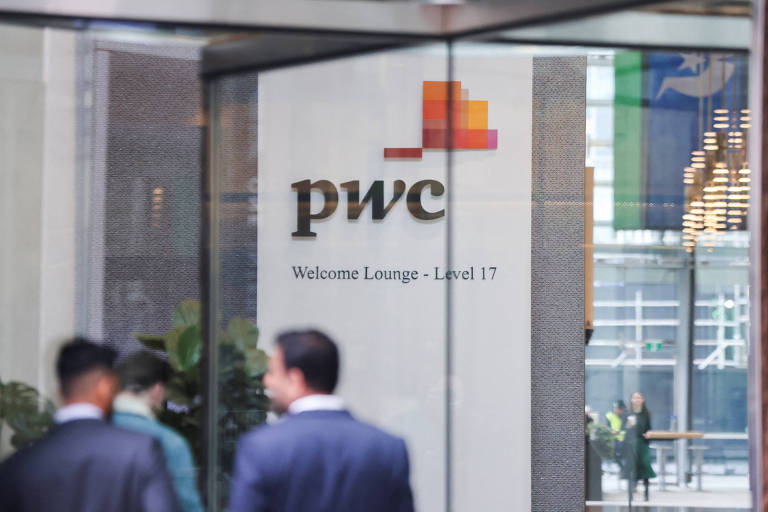 A imagem mostra a entrada do Lounge de Boas-Vindas da PwC, localizado no nível 17. O logotipo da PwC está em destaque, com a inscrição 'Welcome Lounge - Level 17' abaixo. Ao fundo, é possível ver pessoas passando e plantas decorativas.
