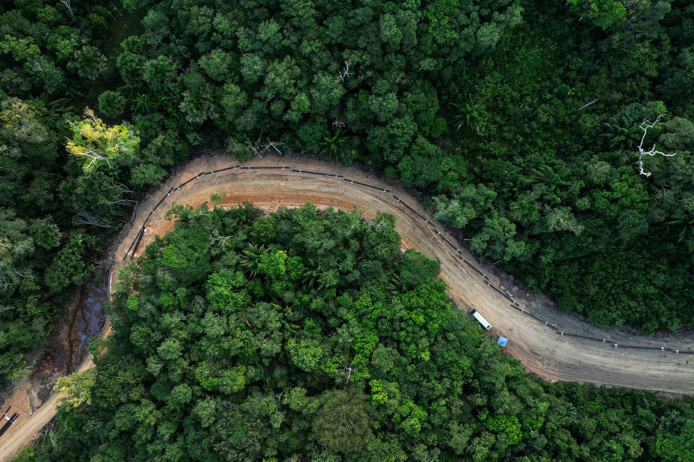 Vista de drone de canos colocados em fila em uma estrada curva aberta no meio da floresta