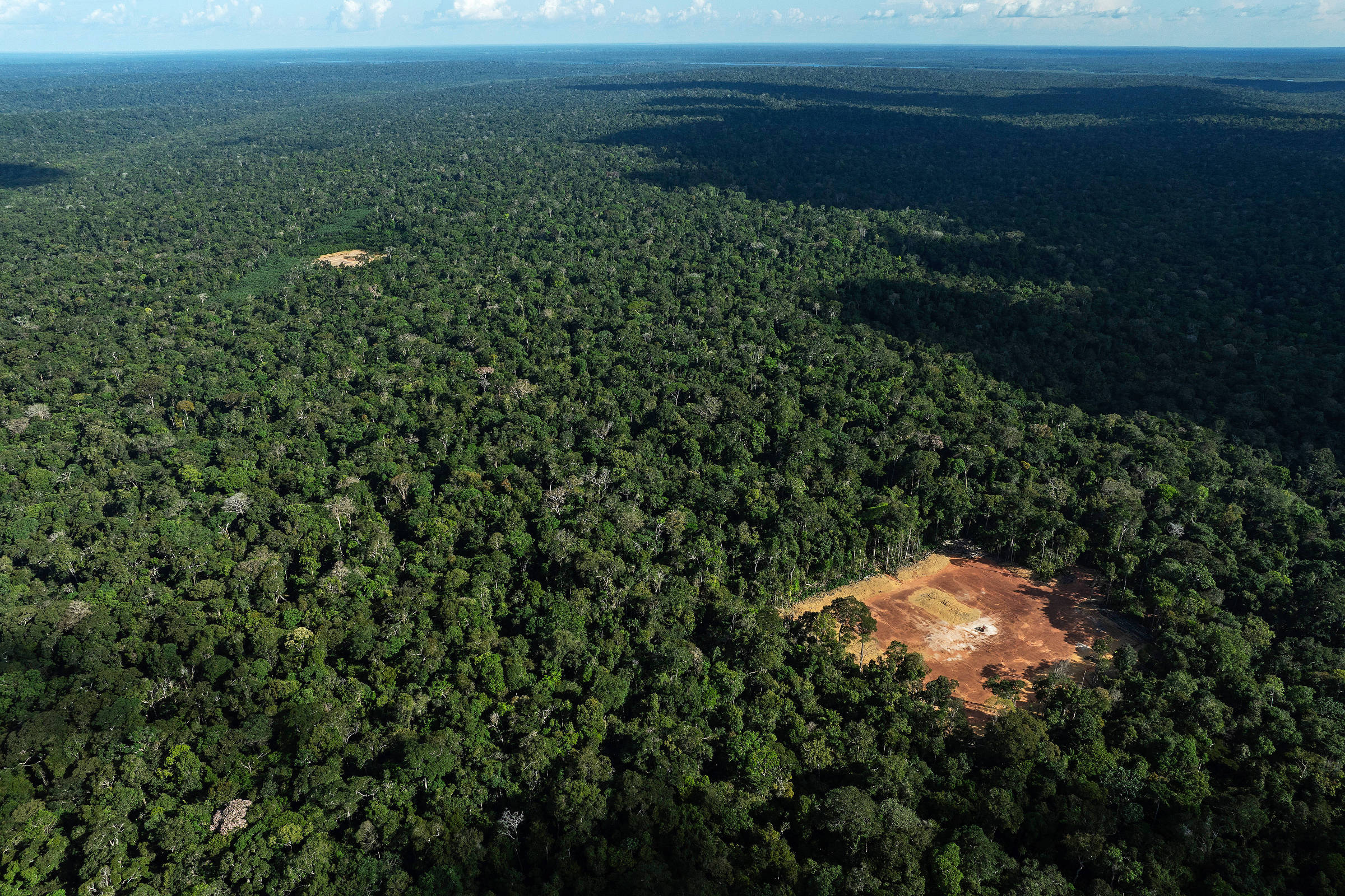 Vista aérea de lugar desmatado em meio à floresta densa