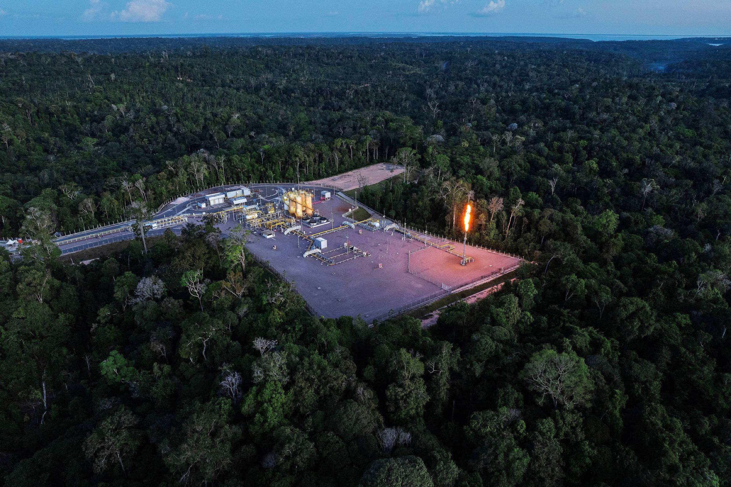 Plataforma com equipamentos no meio da floresta com uma grande chama acesa