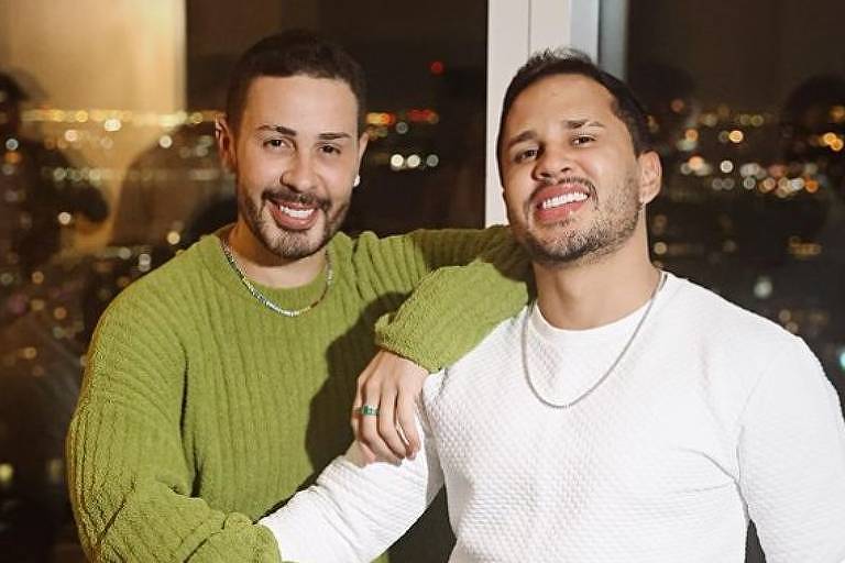 Em foto colorida, dois homens posam sorridentes para foto